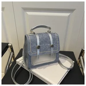 Mini sac à dos en denim gris avec poignées métalliques argentées sur livres