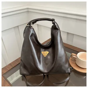 Detail of vintage brown leather tote bag with iconic triangle logo on wooden desk