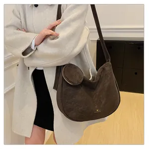Detail of dark brown suede hobo bag featuring a small round coin purse pendant