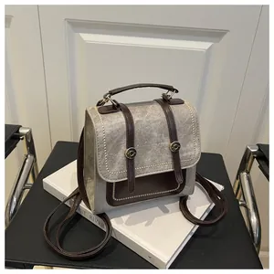 Gros plan d'un sac à dos vintage en toile grise avec bordure marron sur une chaise