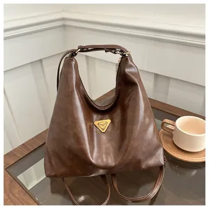 Detail view of large dark brown hobo tote bag featuring a triangle logo and leather texture