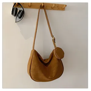Detail of brown suede crescent bag featuring a gold logo and matching round coin purse