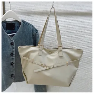 Vista ravvicinata della borsa tote crema con trama in pelle morbida e fibbie in metallo dorato