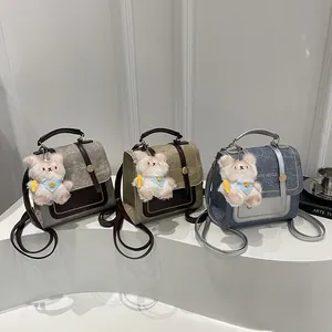 Détails de trois sacs à dos en toile gris, kaki et bleu denim avec pendentif en ours