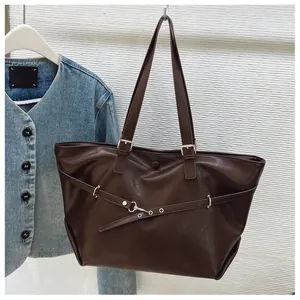 Dettaglio ravvicinato della borsa tote marrone scuro con fibbie in metallo e texture in pelle