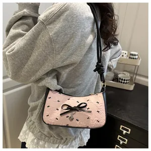 Detail of pink bow shoulder bag with heart pendant worn by model from side back view