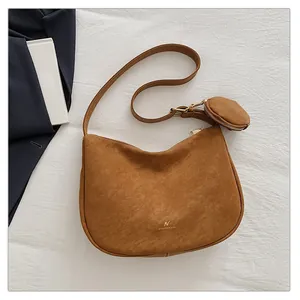 Close-up of brown suede half-moon crossbody bag with matching round coin purse detail