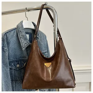 Detail of vintage brown tote bag with metal logo and straps against a denim jacket