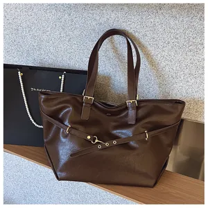 Dettaglio della borsa tote in pelle marrone scuro con tracolle regolabili e fibbie dorate
