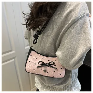 Detail of pink bow shoulder bag with textured fabric and silver heart pendant
