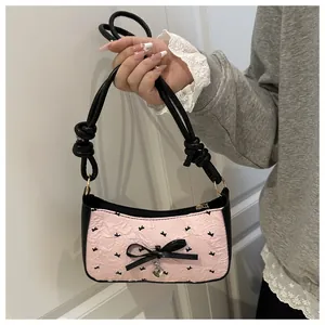 Detail of pink ruffled fabric with black rabbit prints, bow, and heart pendant on the bag