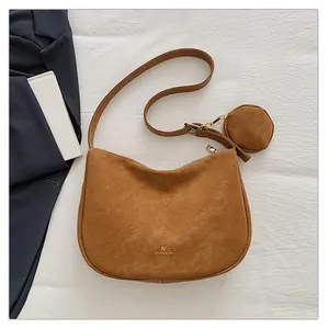 Detail of crescent brown suede crossbody bag with small round coin pouch and gold zipper