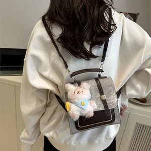 Sac à dos rétro beige et marron minimaliste avec peluche porté par un modèle