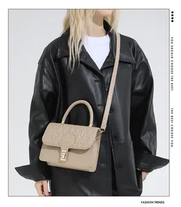 Detail of khaki quilted crossbody bag with gold lock buckle on black leather coat