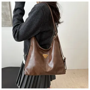 Detail of dark brown vintage leather shoulder bag with metallic triangle hardware
