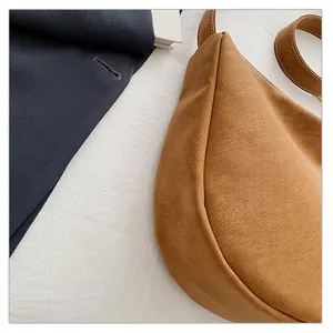 Detailed shot of brown suede hobo bag with vintage contrast stitching and textured fabric