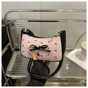Close-up of pink gathered fabric handbag with black bow prints and heart metal charm