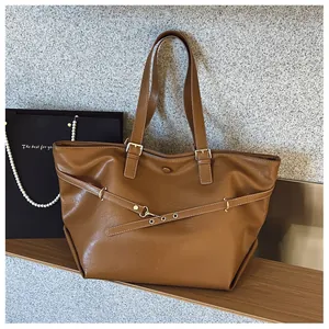 Dettaglio della borsa tote marrone con cinturino, occhielli dorati e trama pelle