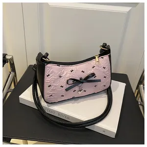 Detailed shot of pink pleated underarm bag with black bow and silver heart charm