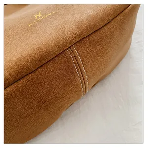 Detailed macro shot of caramel pebbled leather texture with white stitching and gold logo