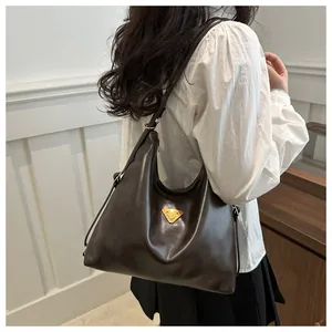 Detailed shot of dark brown polished leather tote bag with gold triangle hardware detail