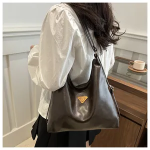 Close-up of brown leather hobo bag with gold triangle logo and smooth polished texture