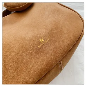 Detail of a brown leather shoulder bag with fine stitching and golden brand logo