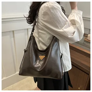 Detail view of large brown vintage tote bag with triangular gold logo and leather texture