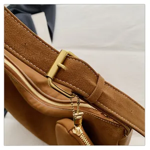 Close-up of brown suede shoulder bag featuring golden metal buckle and zipper detail