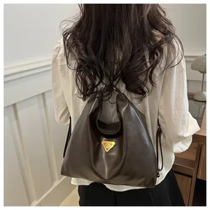 Macro detail of high-quality brown leather hobo bag with gold triangle hardware