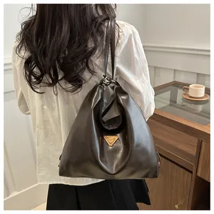 Macro view of polished dark brown leather tote with a metal triangle logo plaque
