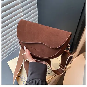Detail der dunkelbraunen Wildleder-Schultertasche mit Wellenklappe und breitem Gurt