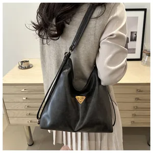 Close-up of black leather tote bag with a golden triangular logo and thin shoulder straps