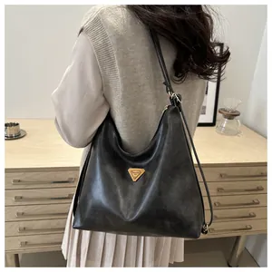 Close-up of textured black leather tote bag with elegant golden triangle logo detail