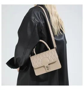 Close-up of beige crossbody bag with wavy quilted pattern and gold metal clasp