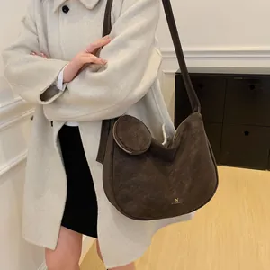 Brown faux suede half-moon shoulder bag with a small round pouch on a model wearing a coat