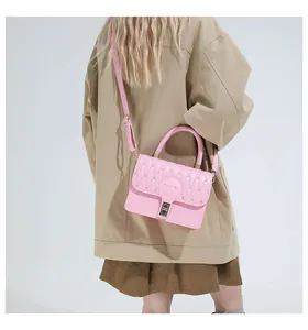 Detail of pink quilted crossbody bag with metal buckle on a beige trench coat
