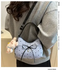 Detalle de bolso bandolera de rayas azules con lazo negro y colgante de conejo de peluche