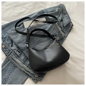 Primer plano del bolso hobo negro de cuero sintético liso sobre fondo de mezclilla