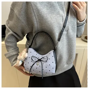 Detail of blue striped crossbody bag with bow, heart print and plush doll charm