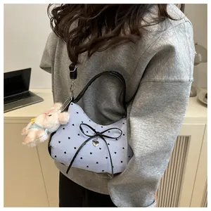 Close-up of blue striped crescent bag with black heart prints and a cute plush bear charm