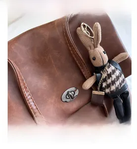 Detail of vintage brown leather tote bag showing oval silver twist lock and knit bunny charm