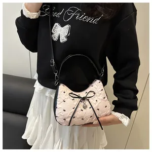 Detail of pink crescent bag with black bow and heart pendant on a shoulder strap