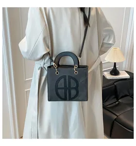 Dettaglio della borsa tote in pelle nera opaca con logo circolare a rilievo e finiture dorate