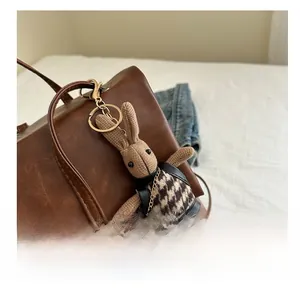 Detail of bunny charm with houndstooth dress hanging on brown leather backpack