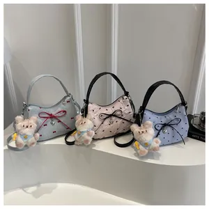 Vista de detalle de tres bolsos de media luna con lazos, flores y colgantes de oso