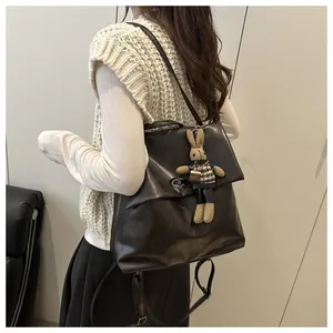 Detail of dark brown leather backpack with metal turn-lock and cute rabbit charm pendant
