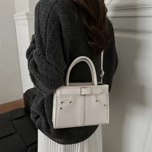 Modern white PU leather handbag with buckle detail shown on a model in a casual setting