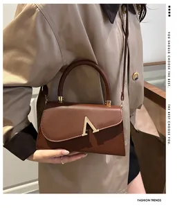 Detail of a brown leather shoulder bag with a gold V-shaped buckle and vintage design