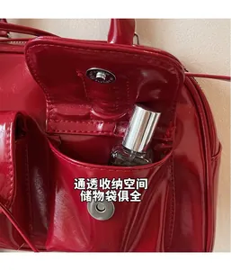 Close-up of a red patent leather shoulder bag detail with a metal magnetic buckle